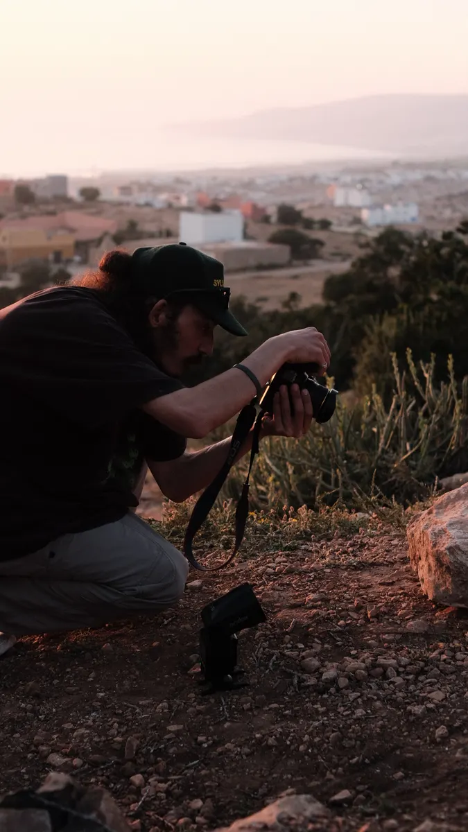 Achraf crouching to shoot over Tamraght at sunset