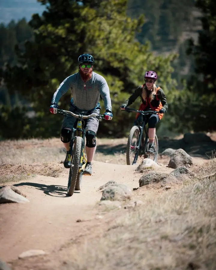 Two bikers on an adventurous trail ride through a scenic forest path during the day.