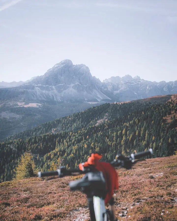 A mountain bike focuses on an expansive view of rugged mountains under a clear sky.