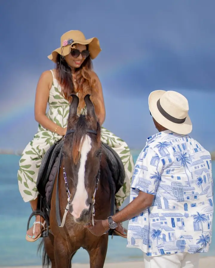 A woman rides a horse on Maafushi beach, Maldives, with a rainbow in the background.