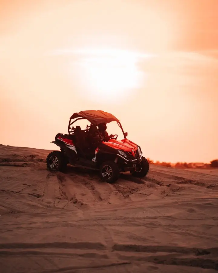 Catch a thrilling off-road adventure in the desert with a red buggy against a stunning sunset backdrop.