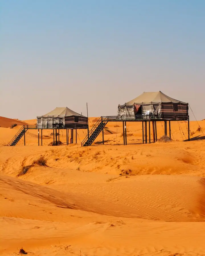 Luxury elevated tents in the stunning desert landscape of Oman, showcasing unique architecture.
