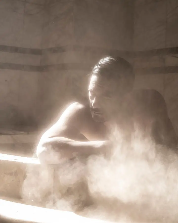 A contemplative man sits amid steam in a traditional Baghdad bath.