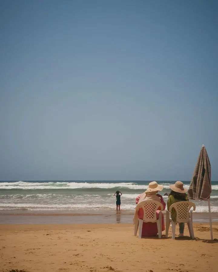 Two adults enjoy a sunny day at Imsouane beach, Morocco.