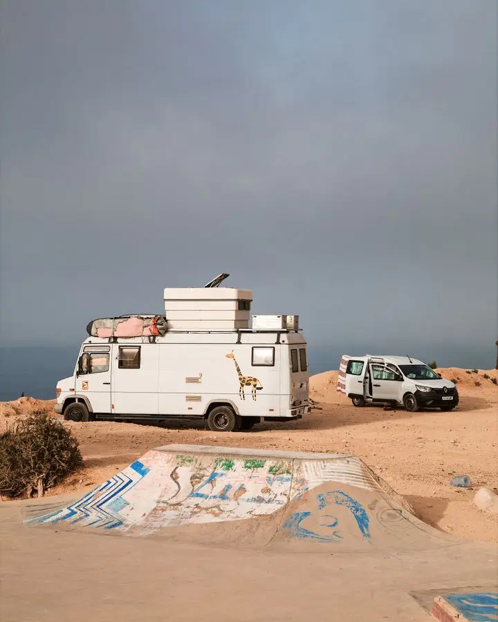 Exploration vehicles parked on Morocco's rugged coastline, showcasing a sense of adventure and travel.