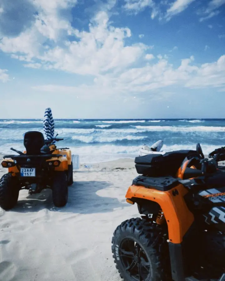 Quads parked on a sandy beach in Edirne, Türkiye with waves crashing under a bright summer sky.