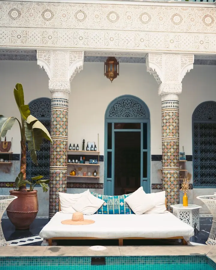 Elegant Moroccan courtyard featuring a luxurious pool and traditional decor.