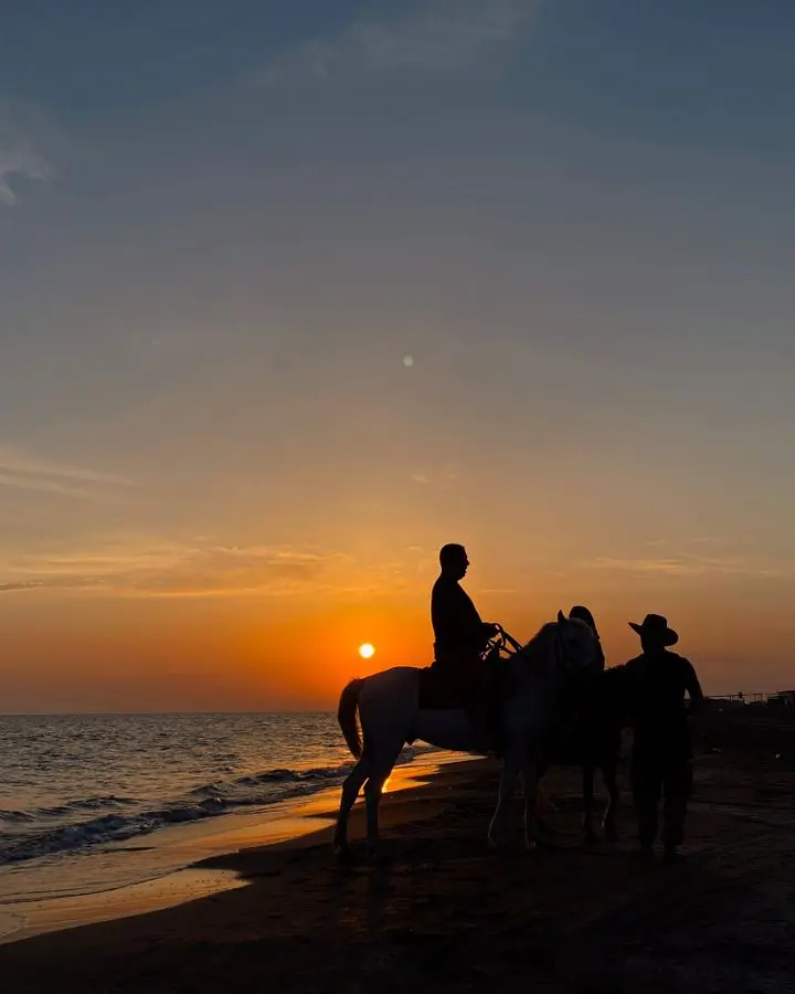 Silhouetted horse riders on Karataş Beach, Turkey, during a stunning sunset.