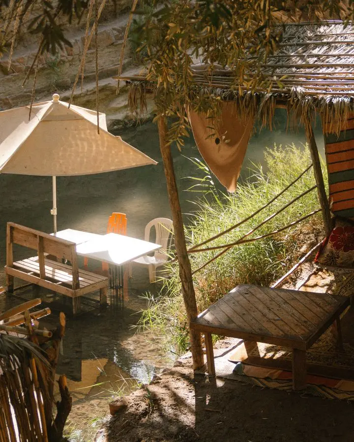 Charming outdoor seating area by the river in Taghazout, Morocco with chairs and umbrellas.