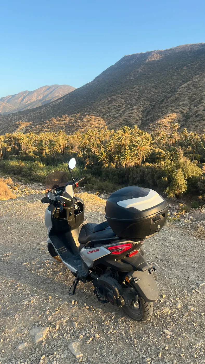 Electric scooter parked on a dirt road below the mountains